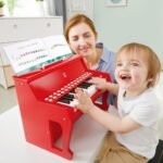 Fëmijë duke luajtur me pianon elektrike prej druri Hape
