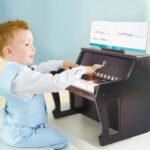 Fëmijë duke mësuar melodi me pianon elektrike prej druri